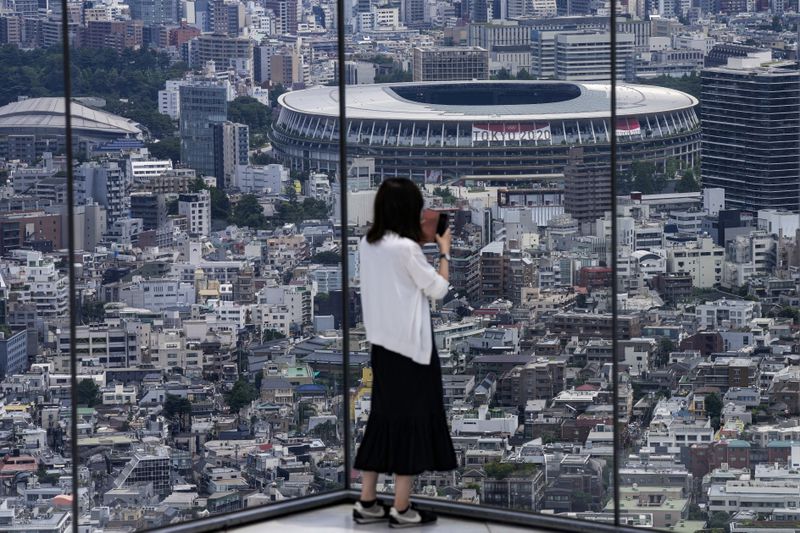 A person wearing a protective mask takes a picture from
an observation deck as National Stadium, where the opening ceremony
of the Tokyo 2020 Olympics will be held, is seen in the background
on Saturday, July 10, 2021, in Tokyo.