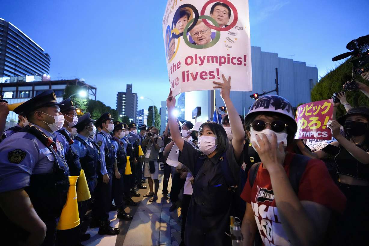 Anti-Olympics protesters, right, stage a rally in front of lines of policemen near National Stadium in Tokyo Friday, July 23, 2021.