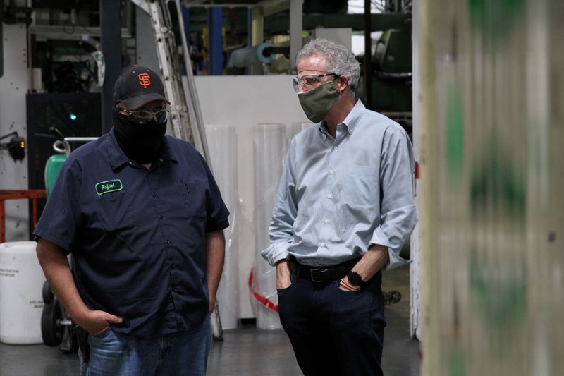 Kevin Kelly, CEO of Emerald Packaging, talks with an employee as they wear protective masks on a production floor of the company, which prints packaging material to be used for produce, amid the coronavirus disease outbreak, in Union City, California, U.S. on May 7, 2020.