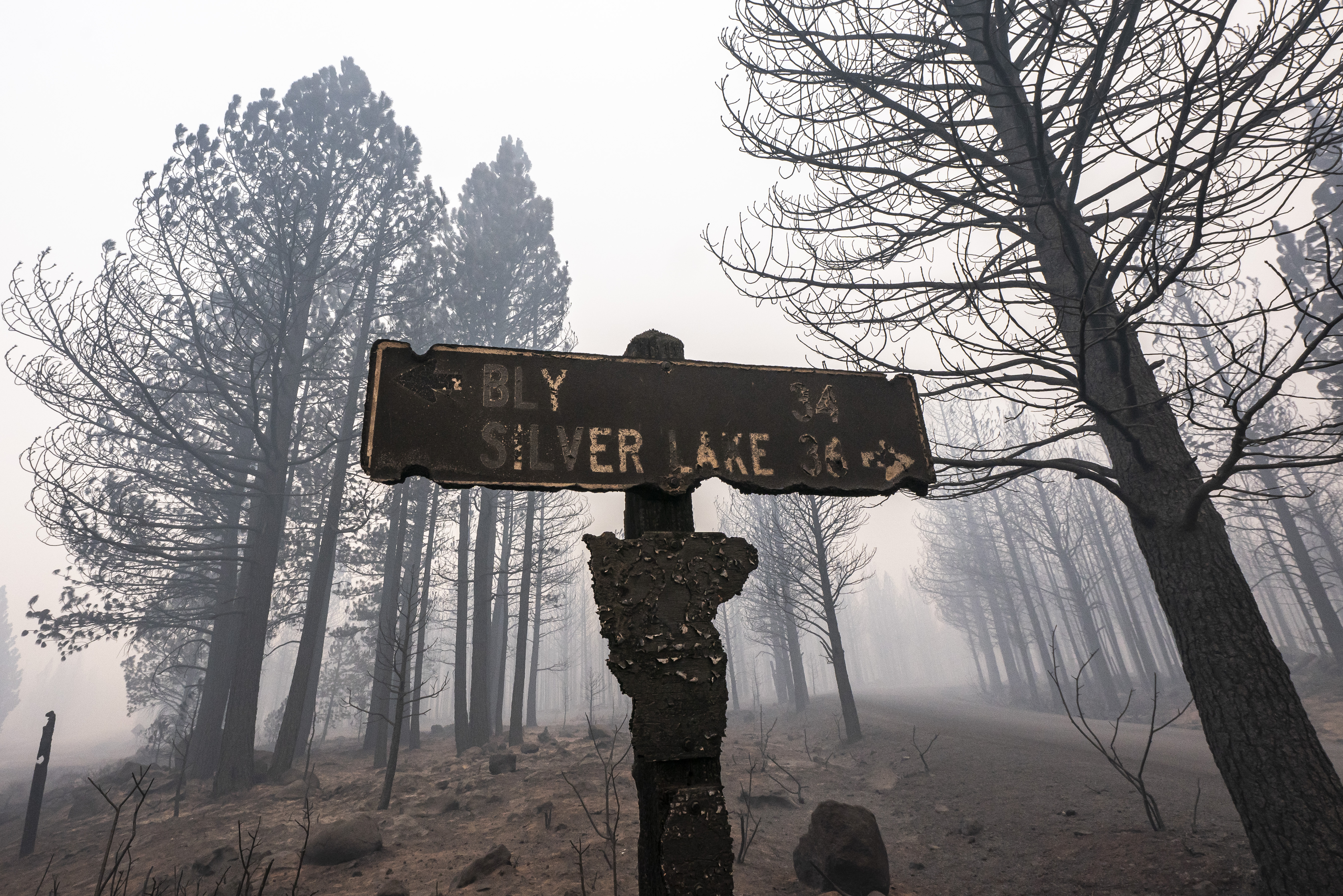 A sign damaged by the Bootleg Fire stands among the haze on Thursday, July 22, 2021, near Paisley, Ore.