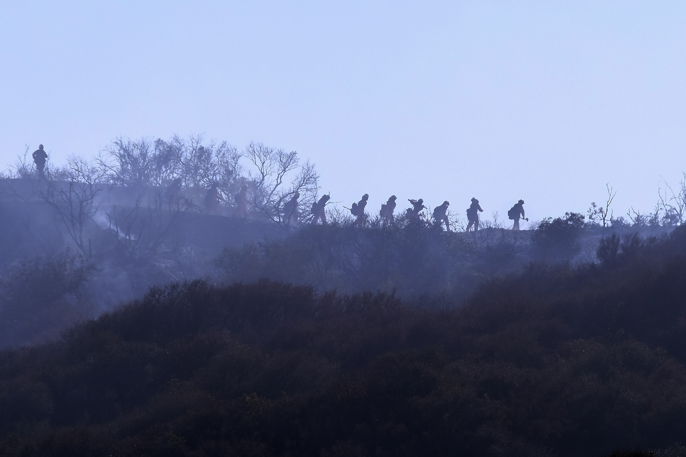 A hotshot hand crew walks in line during a wildfire in Topanga, west of Los Angeles, Monday, July 19, 2021. As drought- and wind-driven wildfires have become more dangerous across the American West in recent years, firefighters have tried to become smarter in how they prepare. 