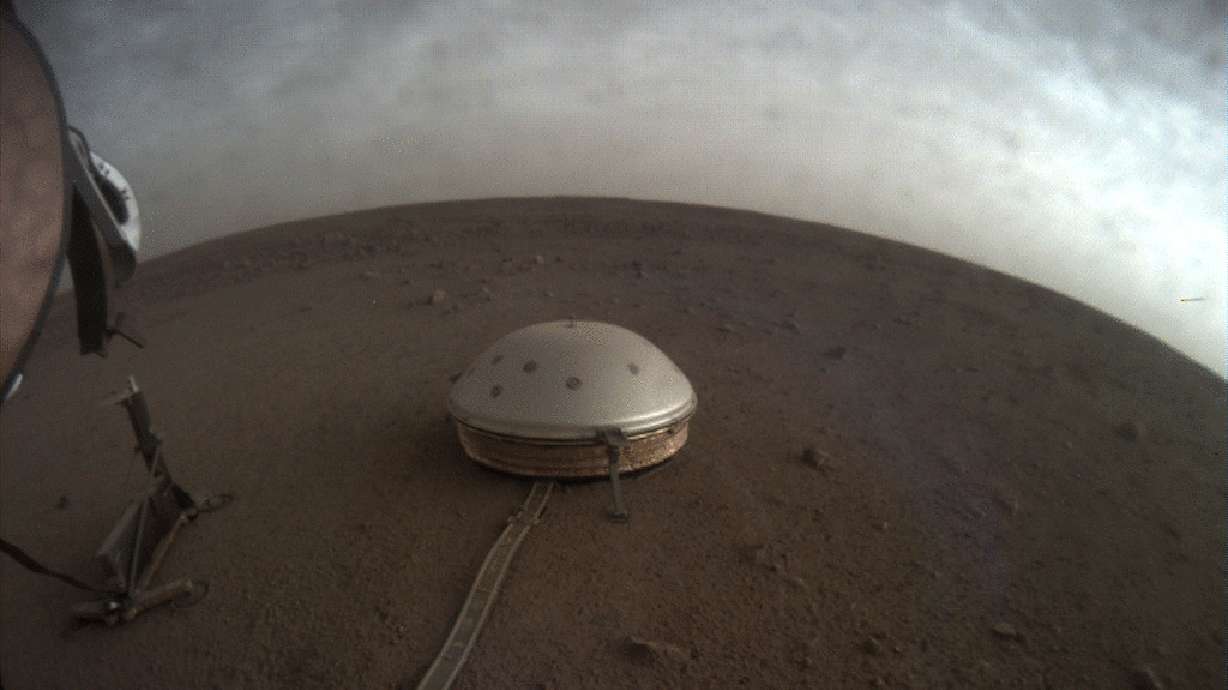 In this undated photo made available by NASA on Thursday, July 22, 2021, clouds drift over the dome-covered SEIS seismometer of the InSight lander on the surface of Mars. The quake-measuring device is providing the first detailed look at the red planet’s interior, revealing a surprisingly thin crust and a molten core. In a series of articles published in July 2021, scientists reported that the Martian crust is within the thickness range of Earth’s. Mars’ mantle, meanwhile, is roughly half that of our own much bigger planet, while the core measured from the dusty surface to dead center is more than 1,000 miles smaller.