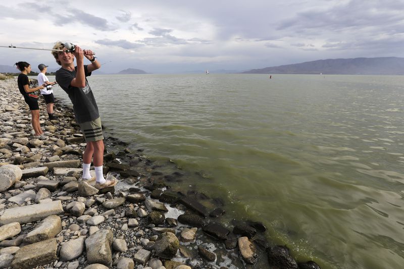 Brian Schulz fishes in Utah Lake, where there are algal
blooms, at the Lindon Marina in Vineyard on Monday, July 19, 2021.
Marli Shaw and Tyler Penrod fish behind him.