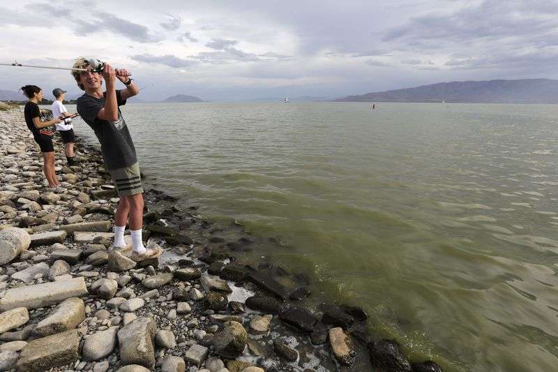 Brian Schulz fishes in Utah Lake, where there are algal
blooms, at the Lindon Marina in Vineyard on Monday, July 19, 2021.
Marli Shaw and Tyler Penrod fish behind him.