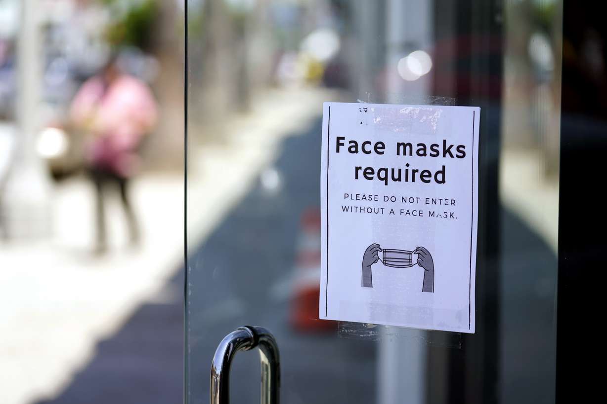 A sign advises shoppers to wear masks outside of a store Monday, July 19, 2021, in Los Angeles. Infections are climbing across the U.S. and mask mandates and other COVID-19 prevention measures are making a comeback in some places as health officials issue increasingly dire warnings about the highly contagious delta variant.