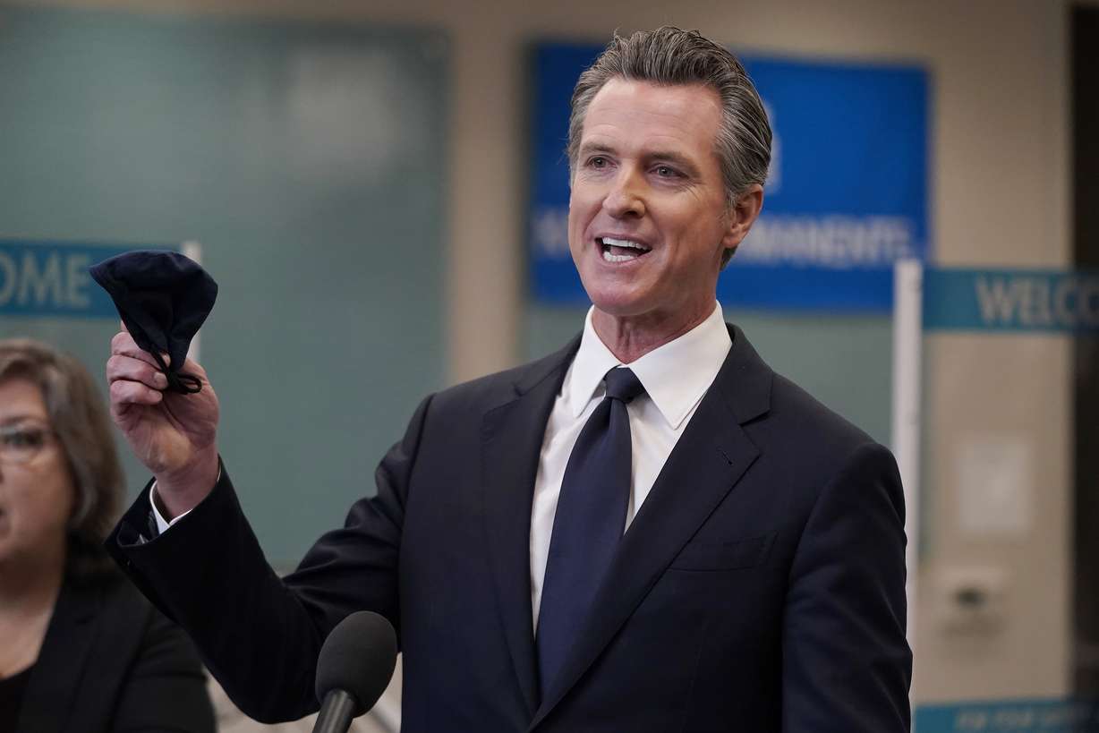 Gov. Gavin Newsom holds a face mask while speaking at a news conference in Oakland, Calif., Monday, July 26, 2021. California will require state employees and all health care workers to show proof of COVID-19 vaccination or get tested weekly.