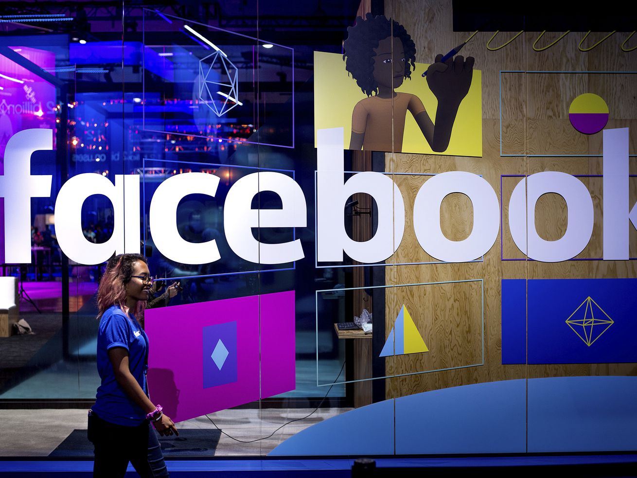 In this April 18, 2017, photo, a conference worker passes a demo booth at Facebook’s annual F8 developer conference in San Jose, Calif. Over 1,300 legislators and policy experts from across the U.S. will be coming to Salt Lake City next week to discuss big tech, social media censorship and misinformation.