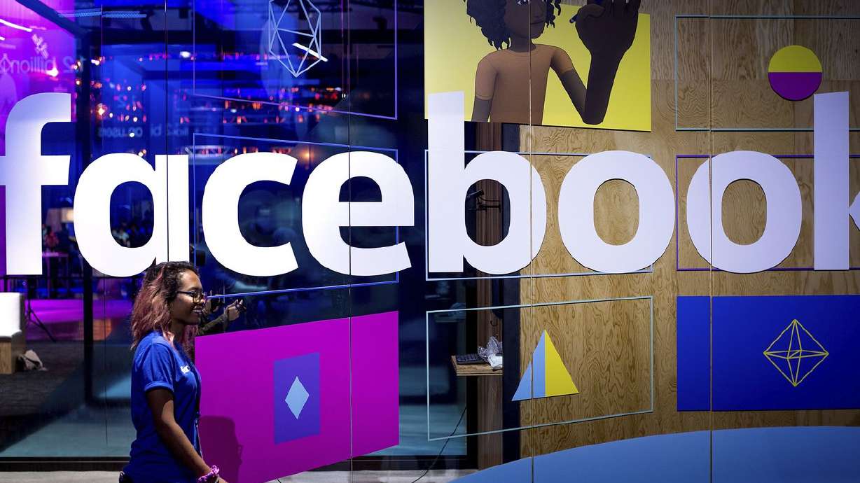 In this April 18, 2017, photo, a conference worker passes a demo booth at Facebook’s annual F8 developer conference in San Jose, Calif. Over 1,300 legislators and policy experts from across the U.S. will be coming to Salt Lake City next week to discuss big tech, social media censorship and misinformation.