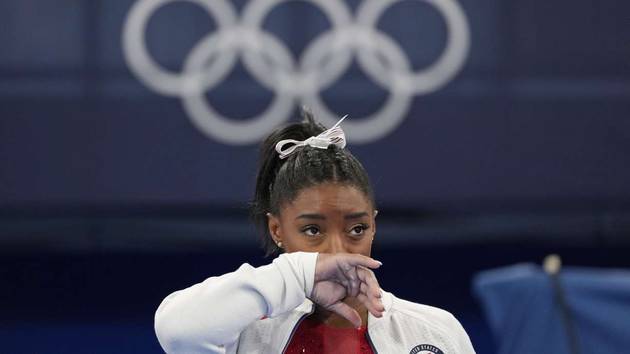 Simone Biles, of the United States, watches gymnasts perform after she exited the team final with an apparent injury, at the 2020 Summer Olympics, Tuesday in Tokyo. Biles huddled with a trainer after landing her vault. She then exited the competition floor with the team doctor.