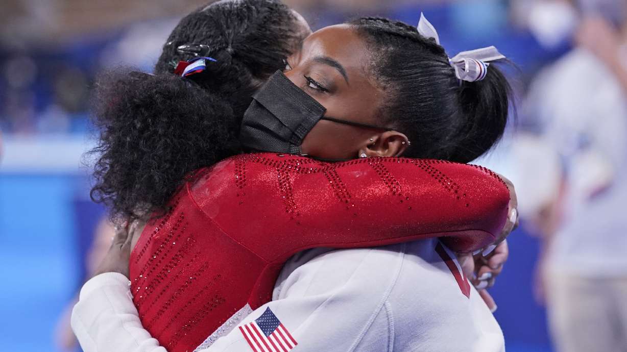 Simone Biles, of the United States, embraces teammate Jordan Chiles after she exited the team final with apparent injury, at the 2020 Summer Olympics, Tuesday, July 27, 2021, in Tokyo. The 24-year-old reigning Olympic gymnastics champion Biles huddled with a trainer after landing her vault. She then exited the competition floor with the team doctor.
