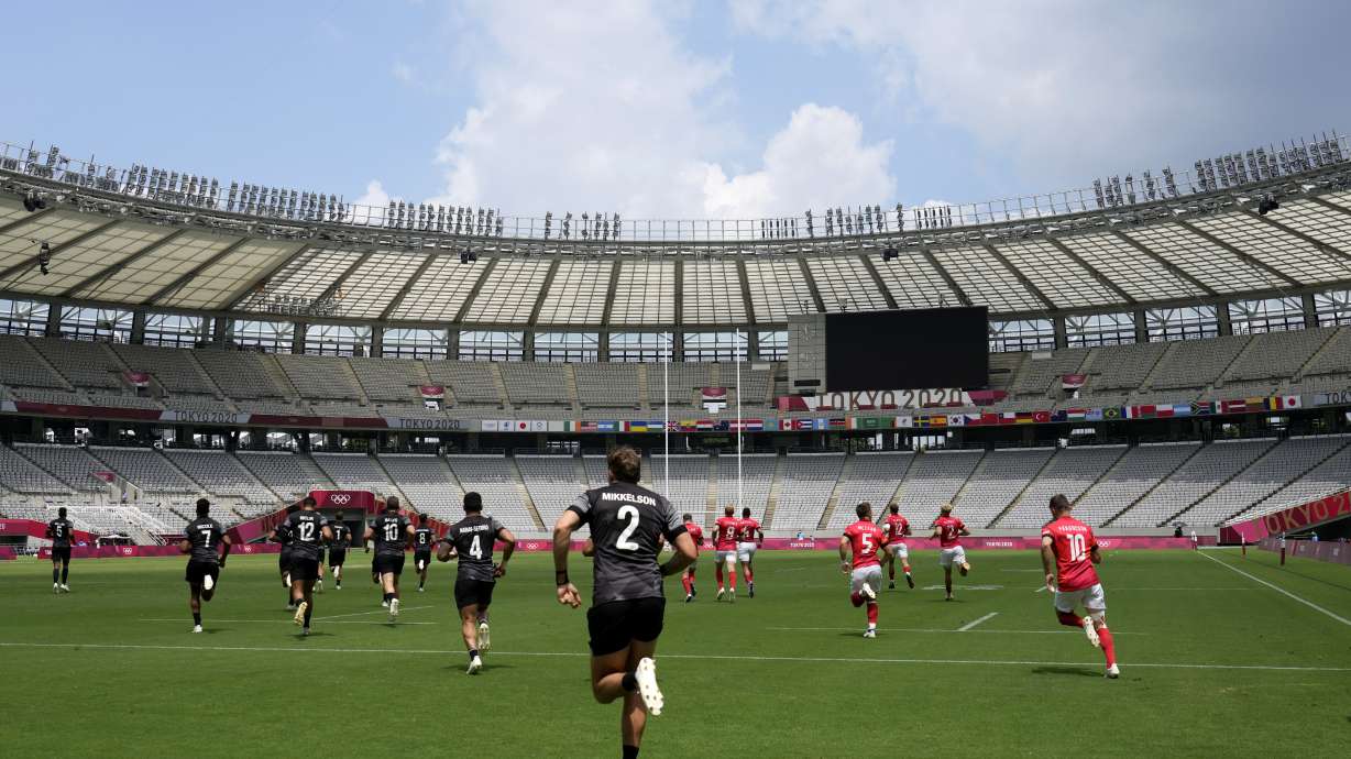Players of New Zealand, in black, and Britain enter the field for their men's rugby sevens semifinal match at the 2020 Summer Olympics, Wednesday, July 28, 2021 in Tokyo, Japan.