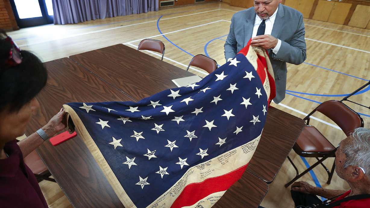 Santa Clara County, Calif., Superior Court Judge Johnny Cepeda Gogo unfurls a 48-star flag similar to those that flew over World War II concentration camps such as Heart Mountain and Topaz at the Salt Lake Buddhist Temple on Wednesday.
