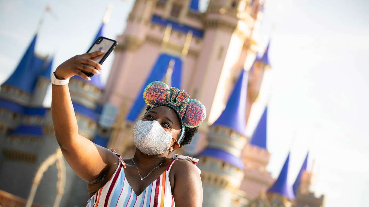 A guest takes a selfie at Walt Disney World Resort on July 11, 2020, in Lake Buena Vista, Florida. Disney World and Disneyland will again require masks indoors.