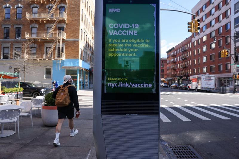 A pedestrian walks past an ad encouraging those eligible to sign up for COVID-19 vaccine appointments in the Manhattan borough of New York City, New York, U.S., March 29. On Thursday, the White House announced new guidelines for federal workers and onsite contractors.