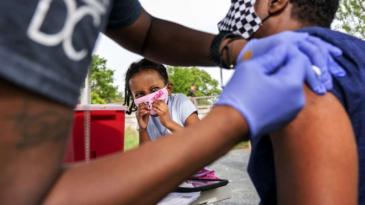 Heran Abebe, 6, reacts as she watches her father Alebel Belay receive a Johnson & Johnson COVID-19 vaccine shot in May at The REACH at the Kennedy Center in Washington. On Thursday, President Joe Biden mandated all federal employees be vaccinated or face other restrictions as coronavirus cases surge in the U.S.