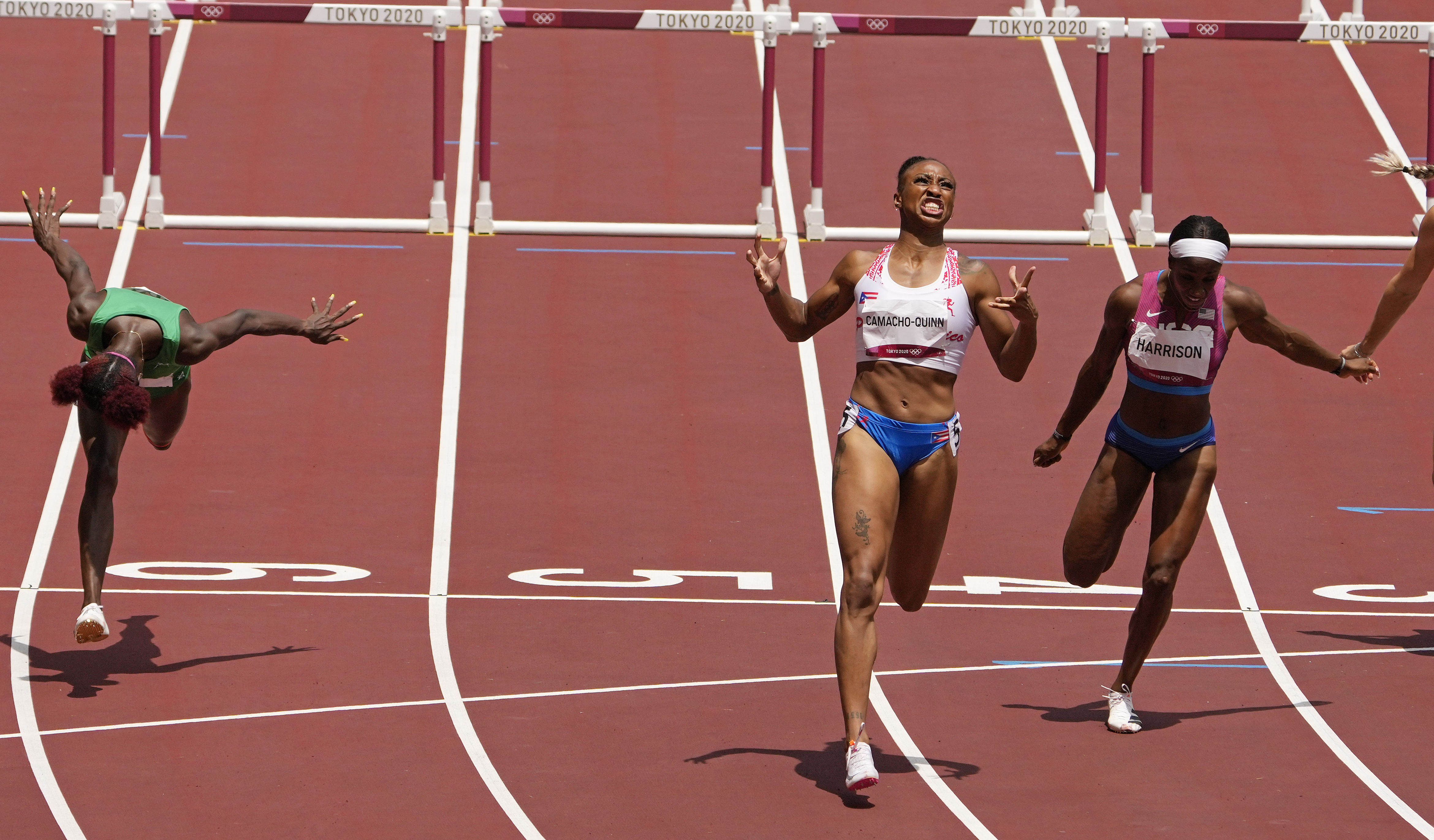 Jasmine Camacho-Quinn, of Puerto Rico, center, celebrates after winning the gold in the women's 100-meters hurdles final ahead of Kendra Harrison, of United States, silver, right, and Tobi Amusan, of Nigeria, fourth, at the 2020 Summer Olympics, Monday, Aug. 2, 2021, in Tokyo, Japan. 