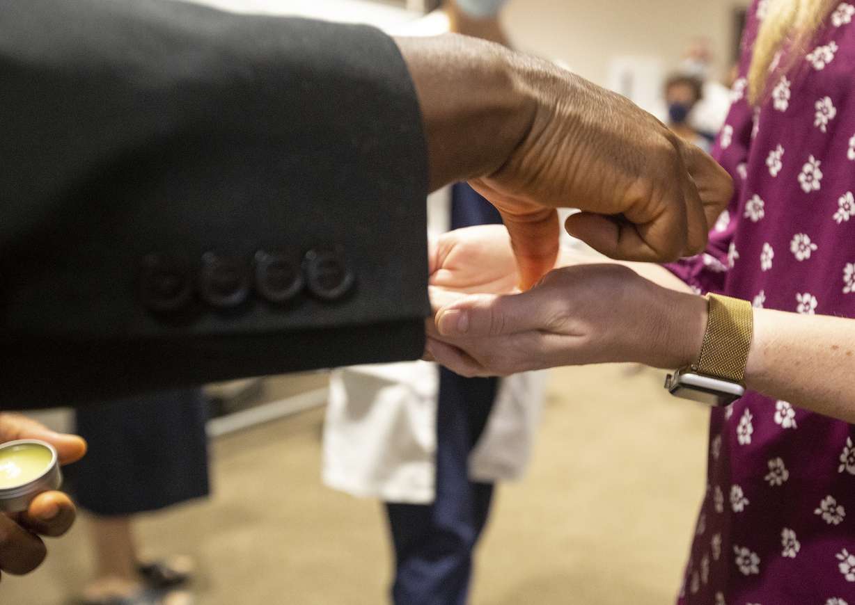 Father Don Ajoko, Phd. anoints the hands of health care workers and members of the nearly three dozen health care workers from around the country to help supplement the staff at Our Lady of the Lake Regional Medical Center in Baton Rouge, La., Monday, Aug. 2, 2021. Louisiana has one of the lowest coronavirus vaccination rates in the nation and is seeing one of the country’s worst COVID-19 spikes.