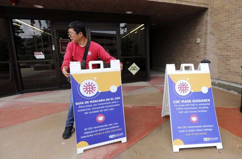 Doobin Im, a Salt Lake County facilities maintenance
worker, puts up new signs at the Salt Lake County Government Center
in Salt Lake City reflecting the Centers for Disease Control and
Prevention’s updated guidance on masks on Monday. The
CDC now recommends masks for all individuals, regardless of
vaccination status, inside public places.