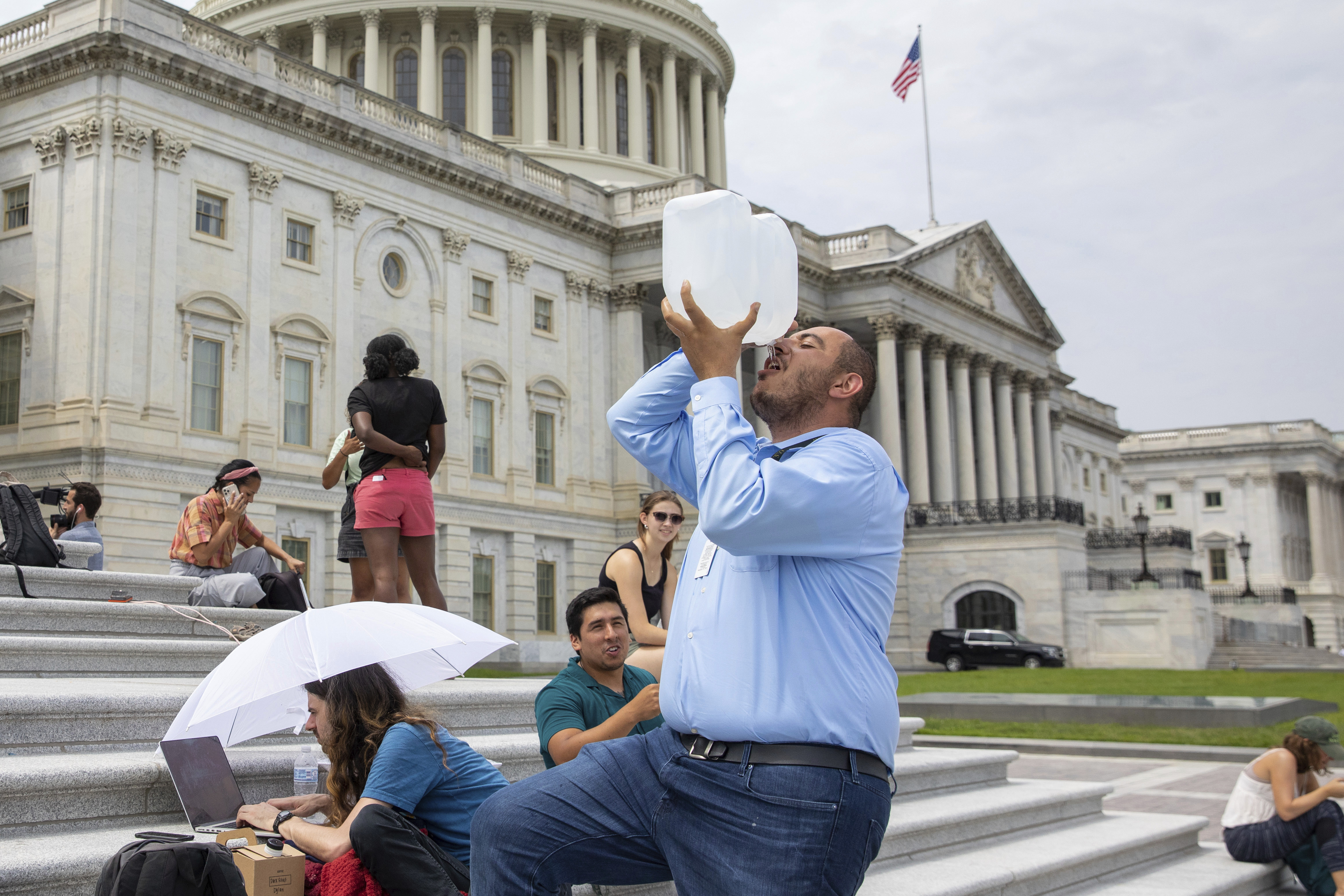 Abbas Alawieh, chief of staff for Rep. Cori Bush, D-Mo., takes a drink of water after sitting on the steps of Capitol Hill in Washington on Tuesday. Bush has been camped outside the U.S. Capitol in protest of the eviction moratorium lapse, since the weekend.