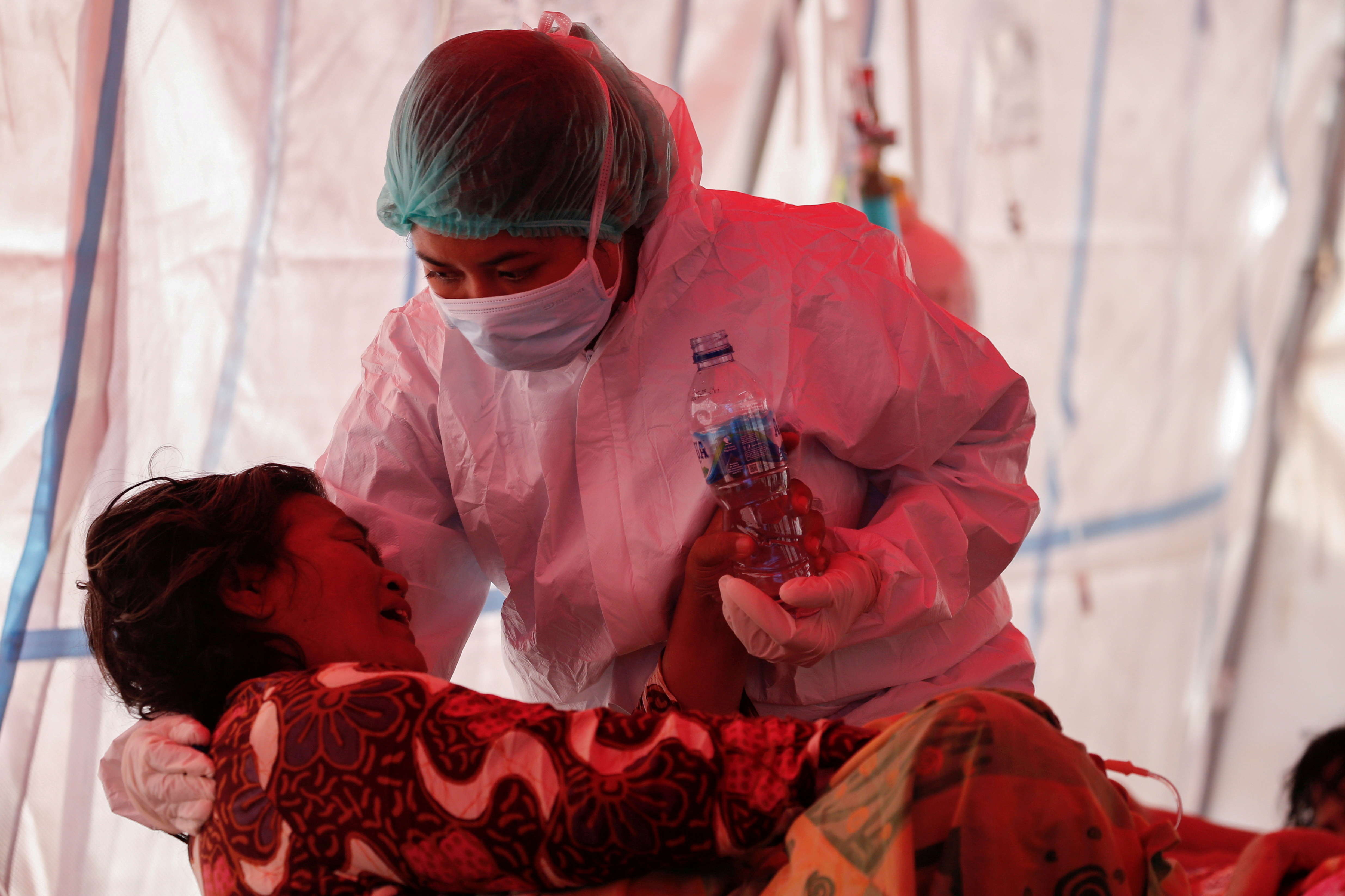 A health care worker in personal protective equipment treats a patient inside a temporary tent erected outside the emergency ward for accommodating the lack of beds at a government-run hospital amid the surge of COVID-19 in Bekasi, on the outskirts of Jakarta, Indonesia, Thursday, July 15.