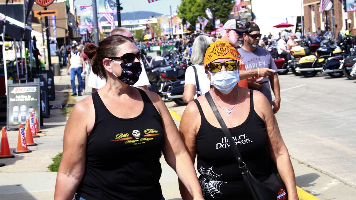 Women walk during opening day of the Sturgis Motorcycle Rally in Sturgis, S.D., Aug. 7, 2020. This year the festival opens Friday, raising COVID fears.