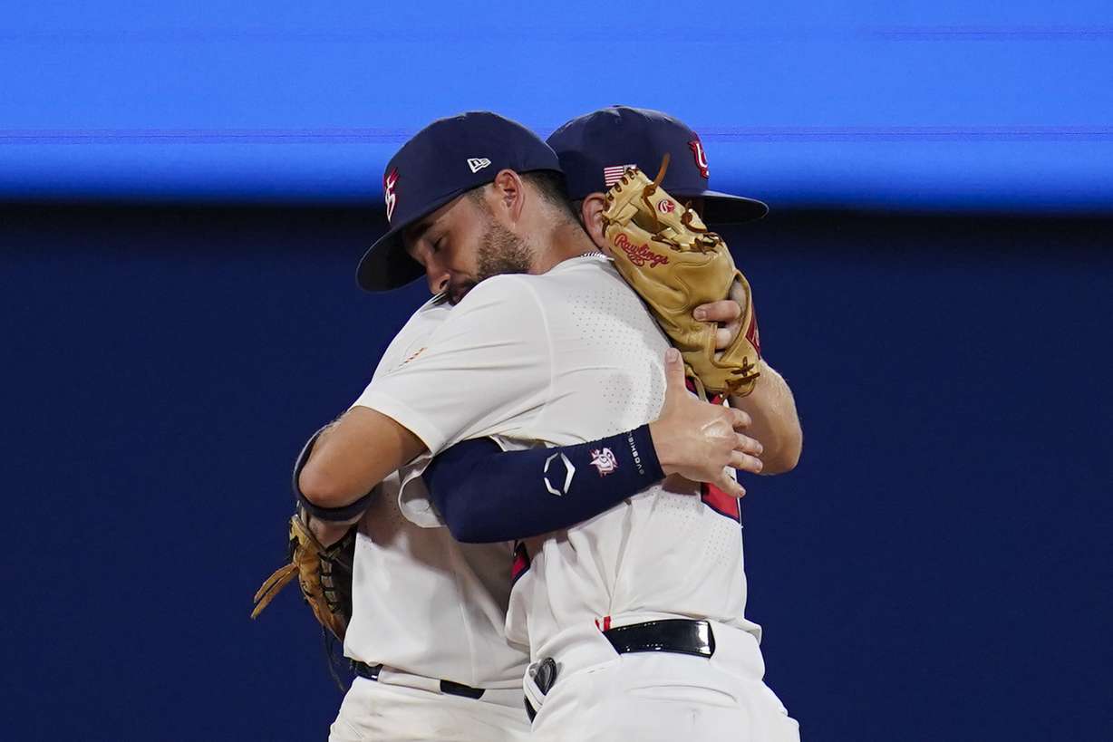An emotional Eddy Alvarez of the United States, front, embraces teammate Nick Allen after a semifinal win over South Korea that clinched a berth in the gold-medal game at the 2020 Summer Olympics, Aug. 5, 2021, in Yokohama, Japan. The United States won 7-2.