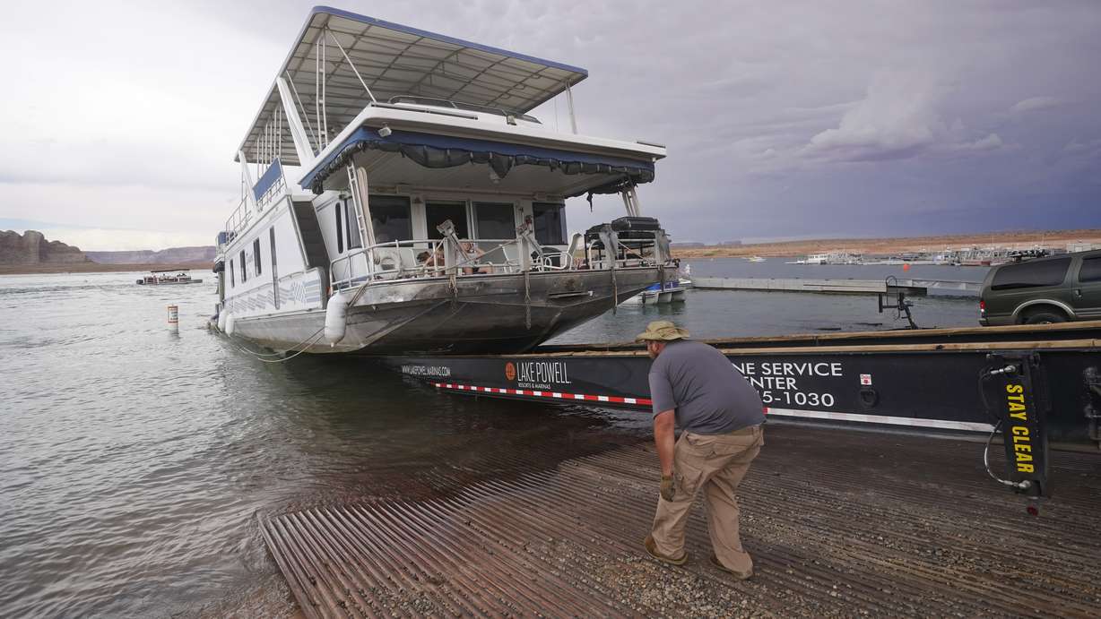 A family's houseboat is pulled from the Wahweap launch ramp after a three-week vacation at Lake Powell Thursday, July 29, 2021, near Page, Ariz. This summer, the water levels hit a historic low amid a climate change-fueled megadrought engulfing the U.S. West. Closed boat ramps have forced some houseboats off the water, leaving tourists and businesses scrambling.