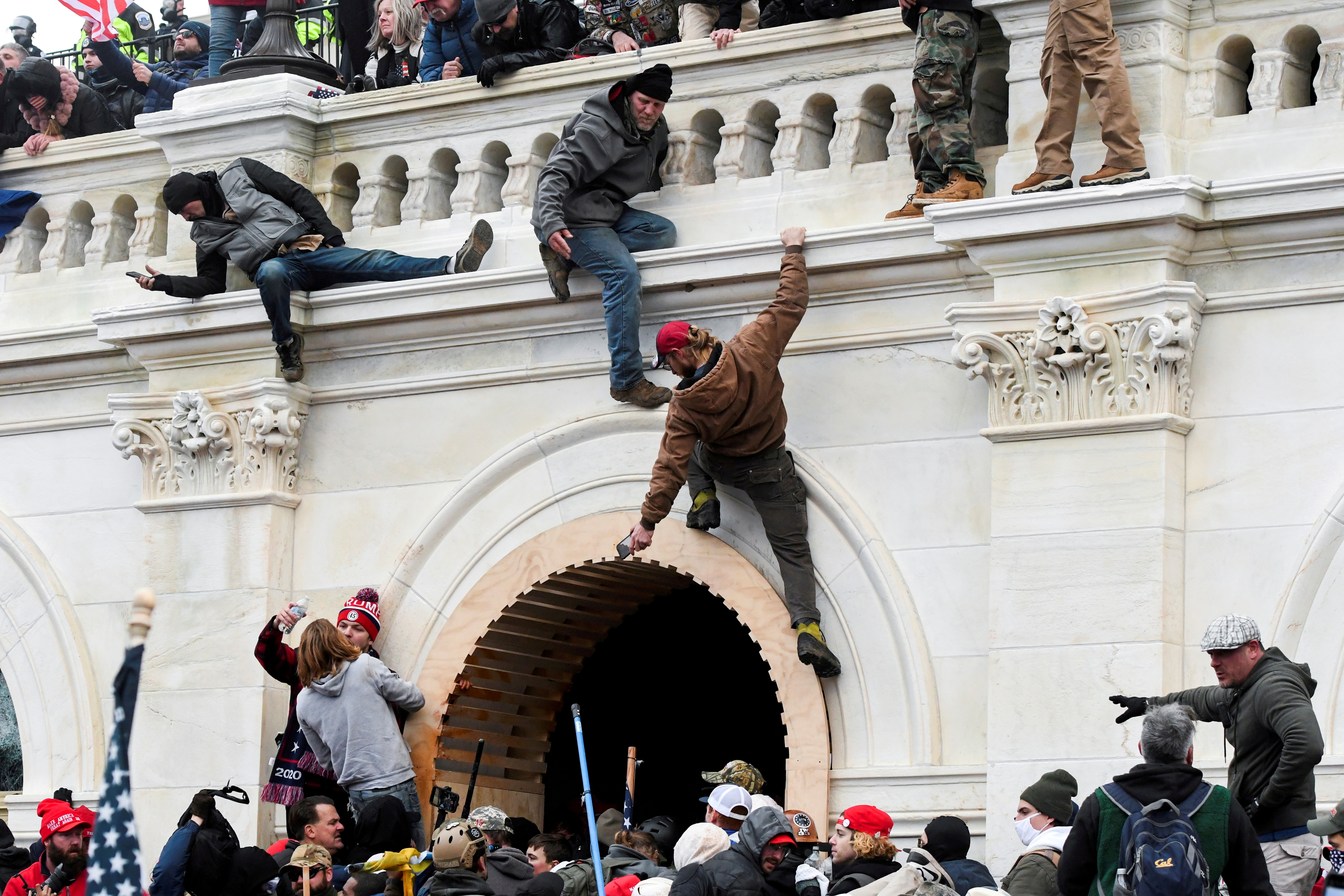 Supporters of President Donald Trump climb on walls at the U.S. Capitol during a protest against the certification of the 2020 U.S. presidential election on Jan. 6. A former boxer charged with punching a Washington police officer in the head during the attack faces a sentence of up to 51 months in prison after pleading guilty on Friday to two felony charges.