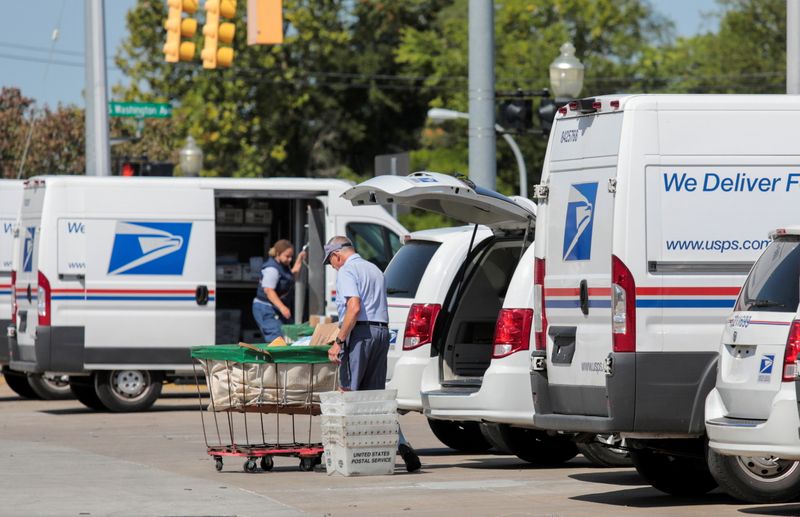 Postal service workers load mail into trucks in Royal Oak, Michigan Aug. 22, 2020. The service on Friday finalized a plan to slow down some first-class mail deliveries.