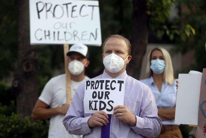 Zachary Noyce holds a sign in support of school mask mandates outside of the Utah State Board of Education office in Salt Lake City on Friday.