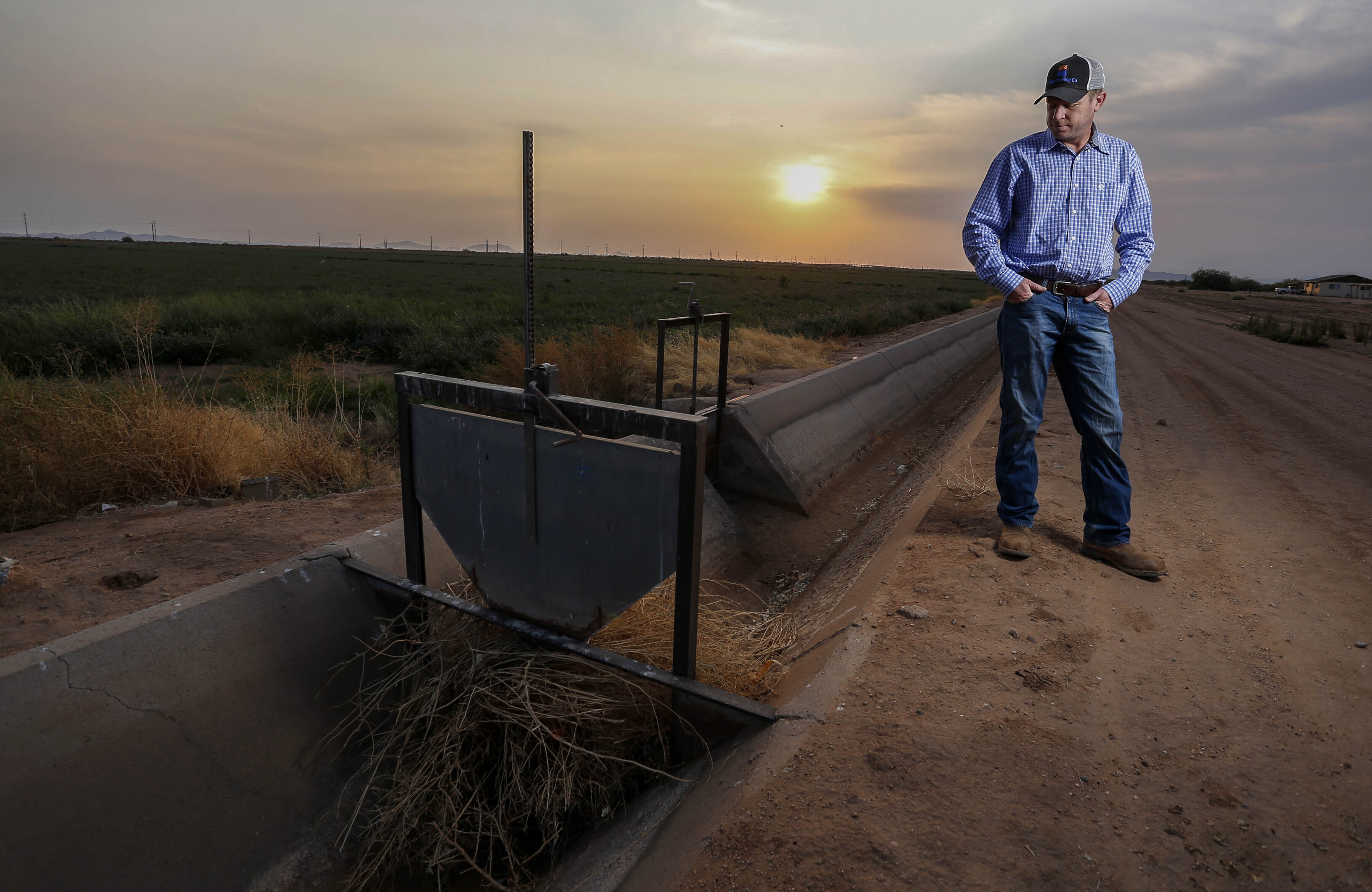 Will Thelander looks into a dry irrigation canal on his property on July 22 in Casa Grande, Ariz. The U.S. Bureau of Reclamation is expected to declare the first-ever mandatory cuts from the Colorado River for 2022.