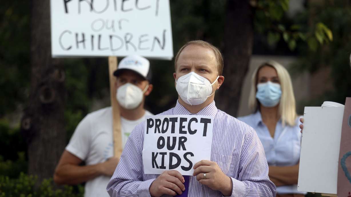 Zachary Noyce holds a sign in support of school mask mandates outside of the Utah State Board of Education office in Salt Lake City on Friday, Aug. 6, 2021.