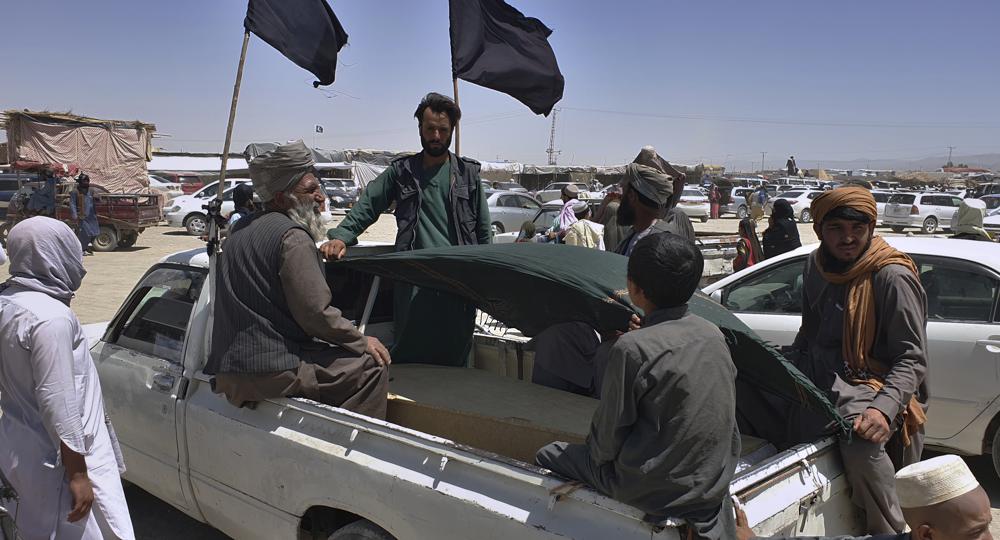 Stranded people sit around a coffin of their relative, loaded in a pickup truck moving towards the Afghan side at a border crossing point, in Chaman, Pakistan, Friday. Pakistan opened its Chaman border crossing for people who had been stranded in recent weeks.