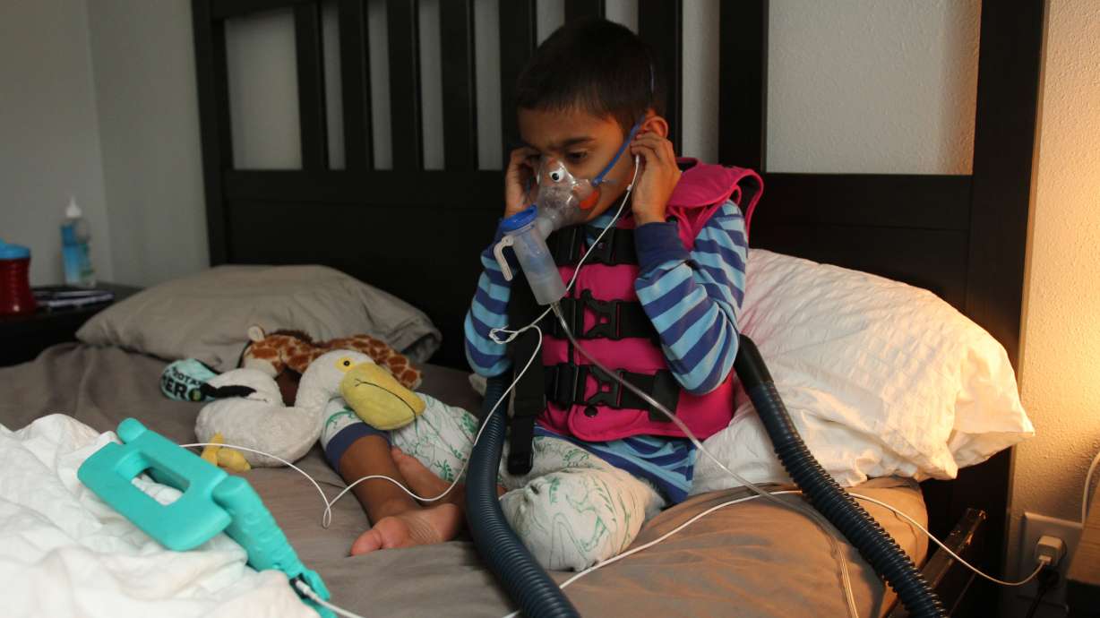 Ethan Chandra, 7, sits in quarantine with his stuffed animal, Pelly the Pelican, and medical equipment to help him breathe. He has heterotaxy, a condition that affects his internal organs and his immune system. He was diagnosed with COVID-19 on July 29.