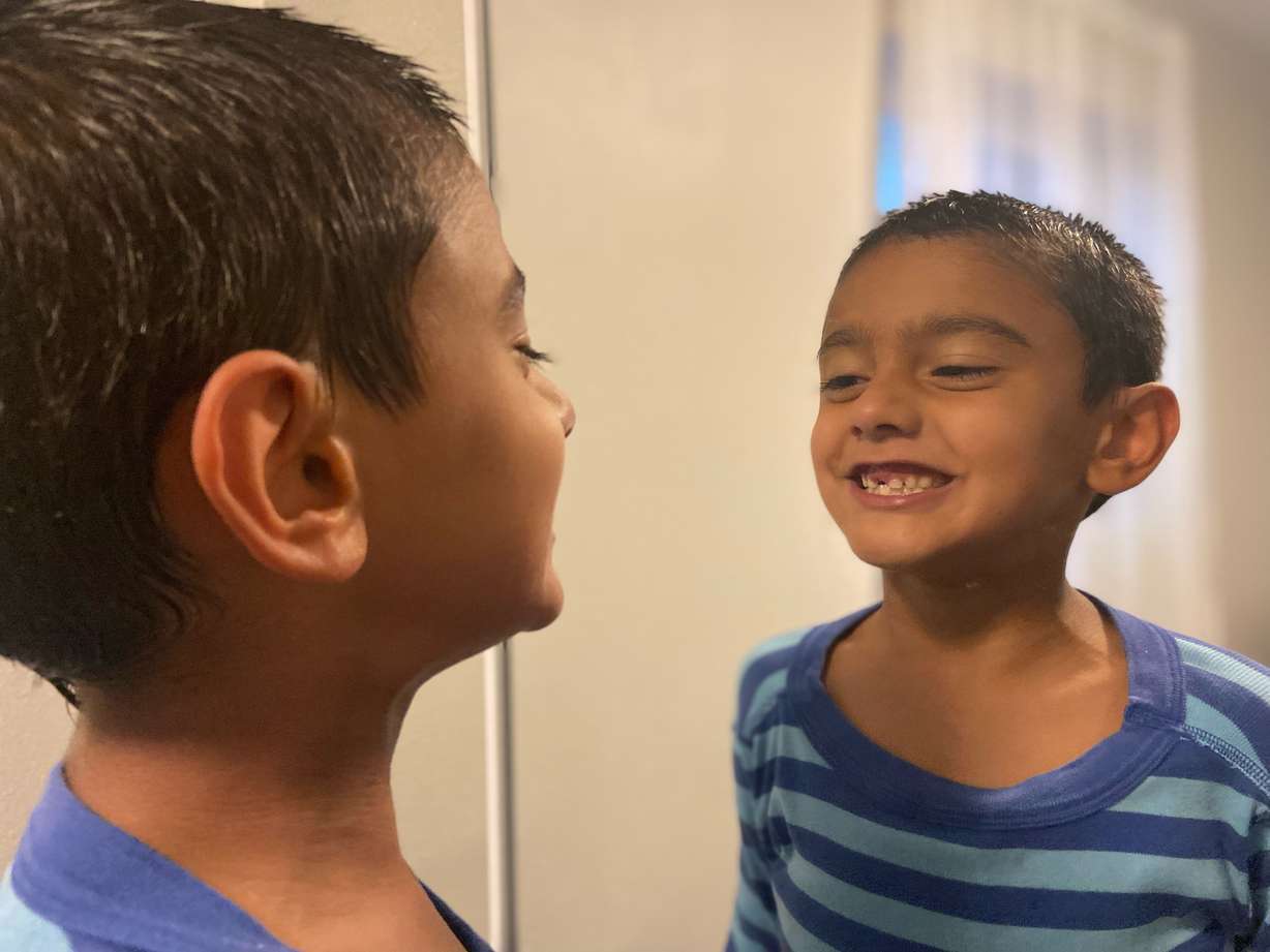 Ethan Chandra, 7, smiles in the mirror showing off his lost tooth. He has heterotaxy, a condition that affects his internal organs and his immune system. He was diagnosed with COVID-19 on July 29.
