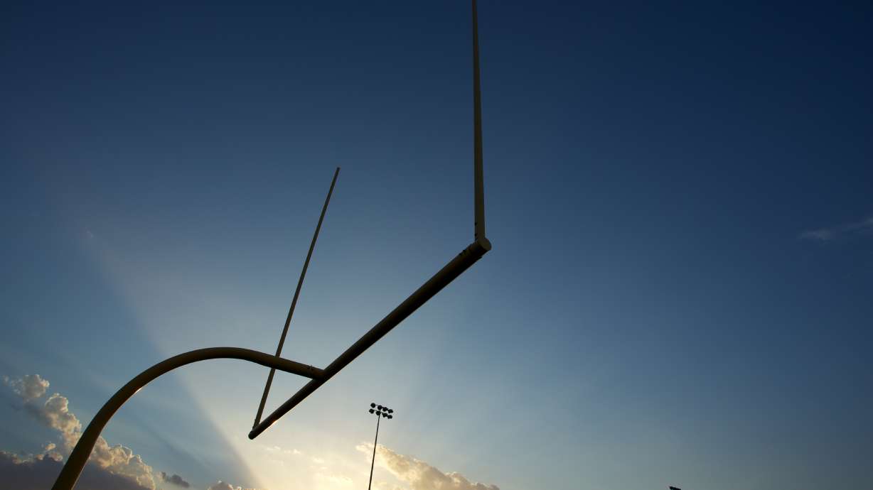 Football field goal posts, or uprights, backlit by a setting sun.