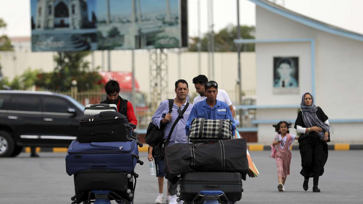 Passengers walk to the departures terminal of Hamid Karzai International Airport in Kabul, Afghanistan, Saturday. As a Taliban offensive encircles the Afghan capital, the airport is the only way out for those fleeing the war, and only one way in for U.S. troops sent to protect American diplomats still on the ground.