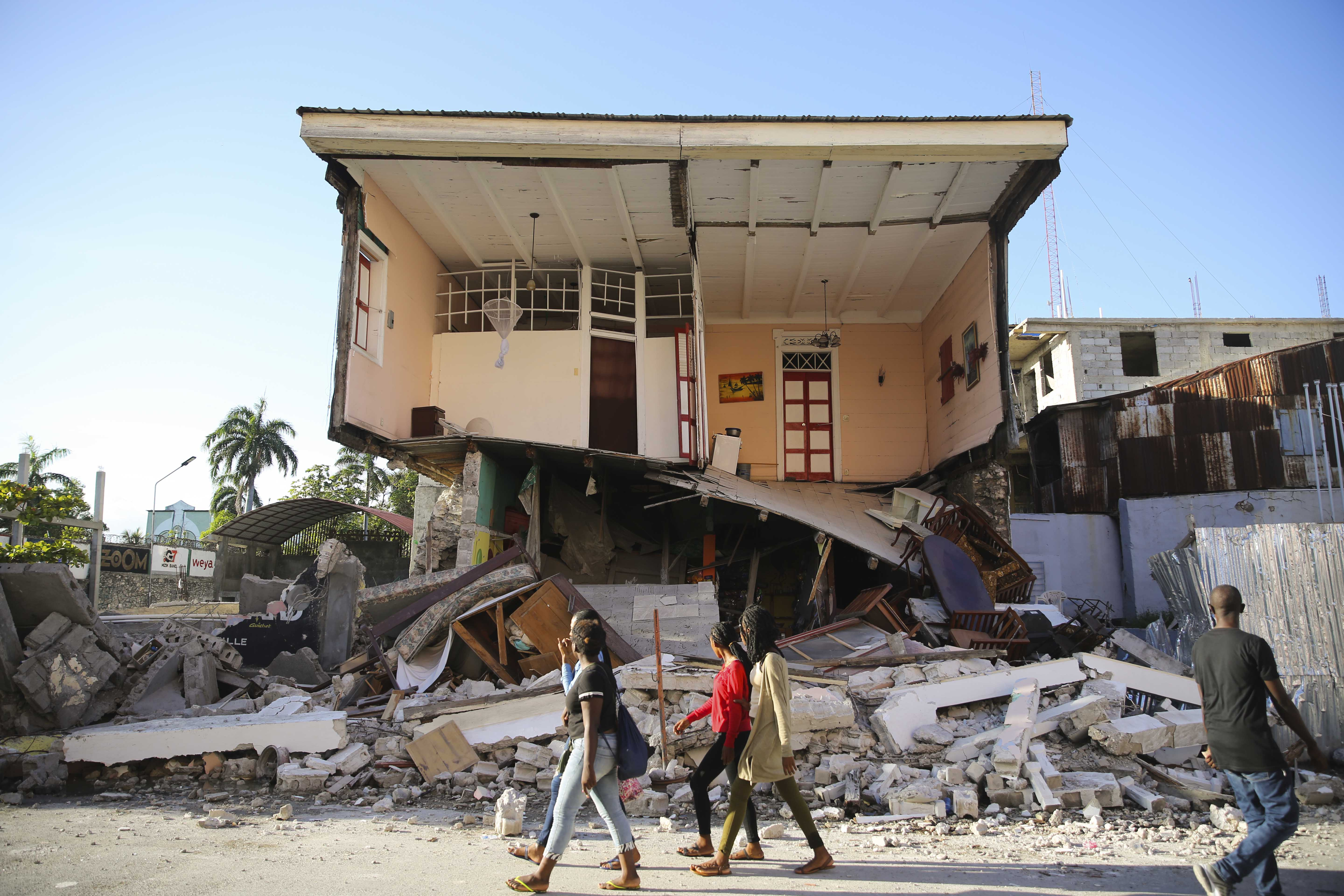 People walk past a home destroyed by the earthquake in Les Cayes, Haiti, Saturday. A 7.2 magnitude earthquake struck Haiti on Saturday, with the epicenter about 125 kilometers (78 miles) west of the capital of Port- au-Prince, the US Geological Survey said.
