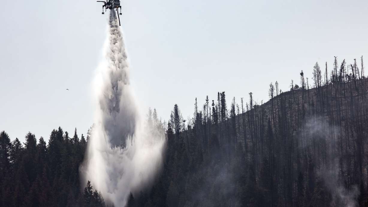 A helicopter drops water on hot spots as crews fight the Parleys Canyon Fire near Park City on Monday.