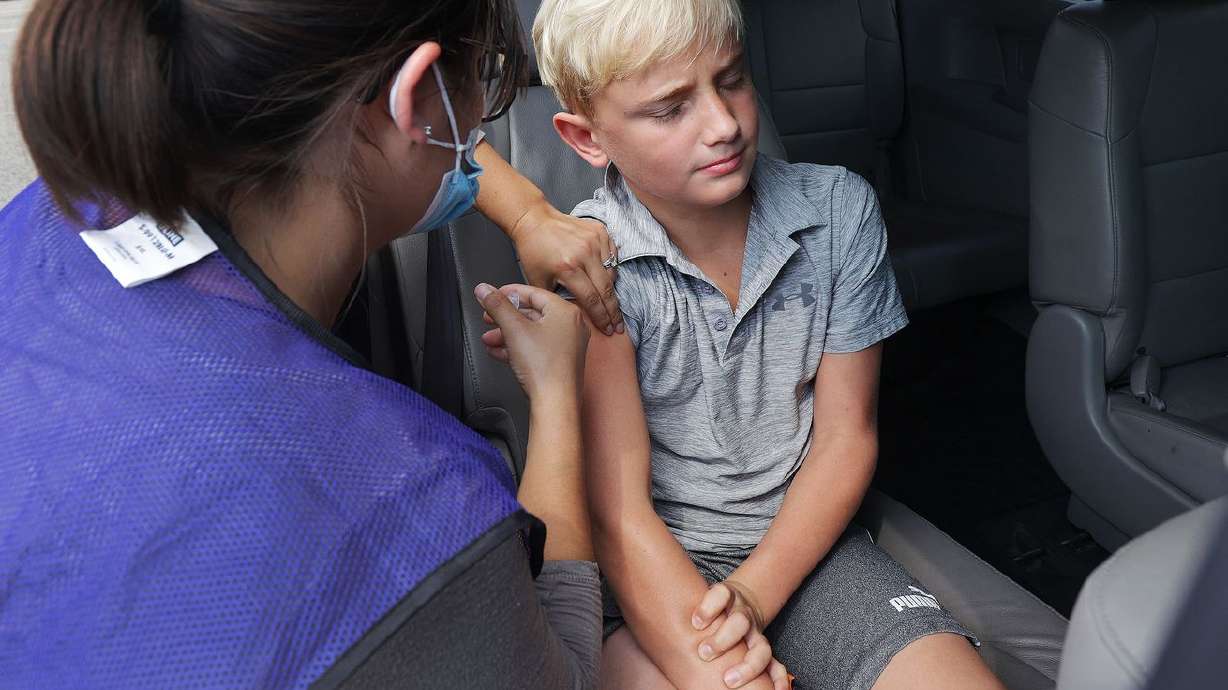 Utah Air National Guard medic Stephanie Young gives Max Lind, 12, a COVID-19 vaccine during a Utah County Health clinic at Equestrian Park in Highland on Thursday, Aug. 5, 2021. The Utah Department of Health reported 2,718 new cases since Friday, as well as 12 deaths.