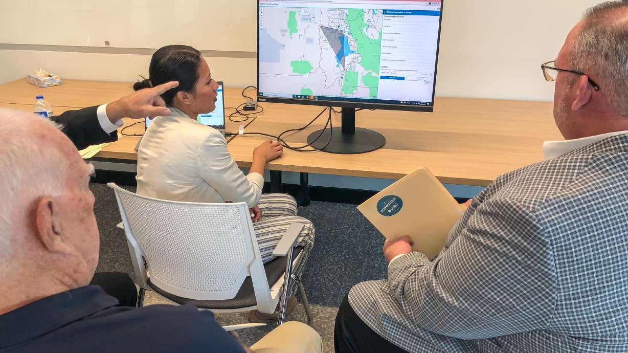 A Utah employee shows members of the Coalition of Utah Mayors how to use an online tool set up for the Utah Independent Redistricting Commission during an event at the Utah State Office Building in Taylorsville on Monday. The tool allows users to create their own redistricting maps as a form of public comment.