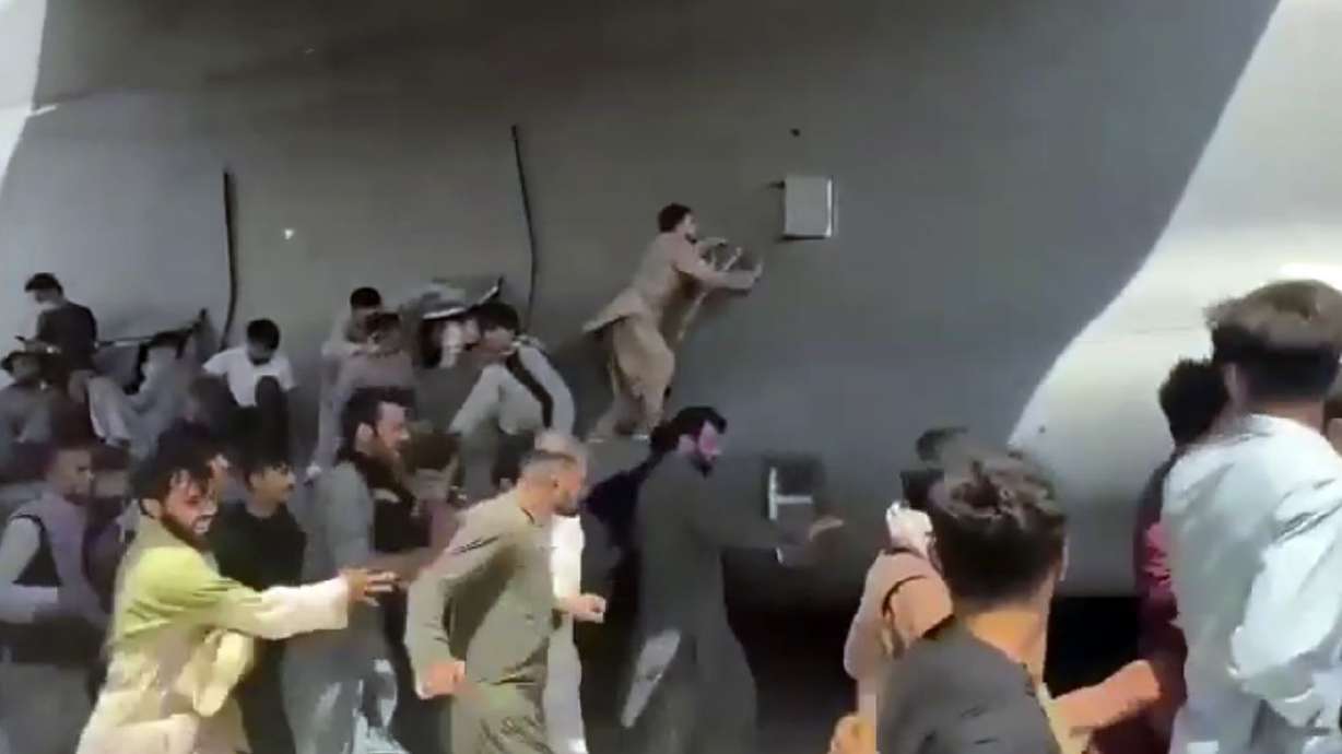 Hundreds of people run alongside a U.S. Air Force transport plane as it moves down a
runway of the international airport in Kabul, Afghanistan, on Monday. Some citizens so desperate to escape the Taliban
capture of their country that they held onto the American military jet as it took off and plunged to death.