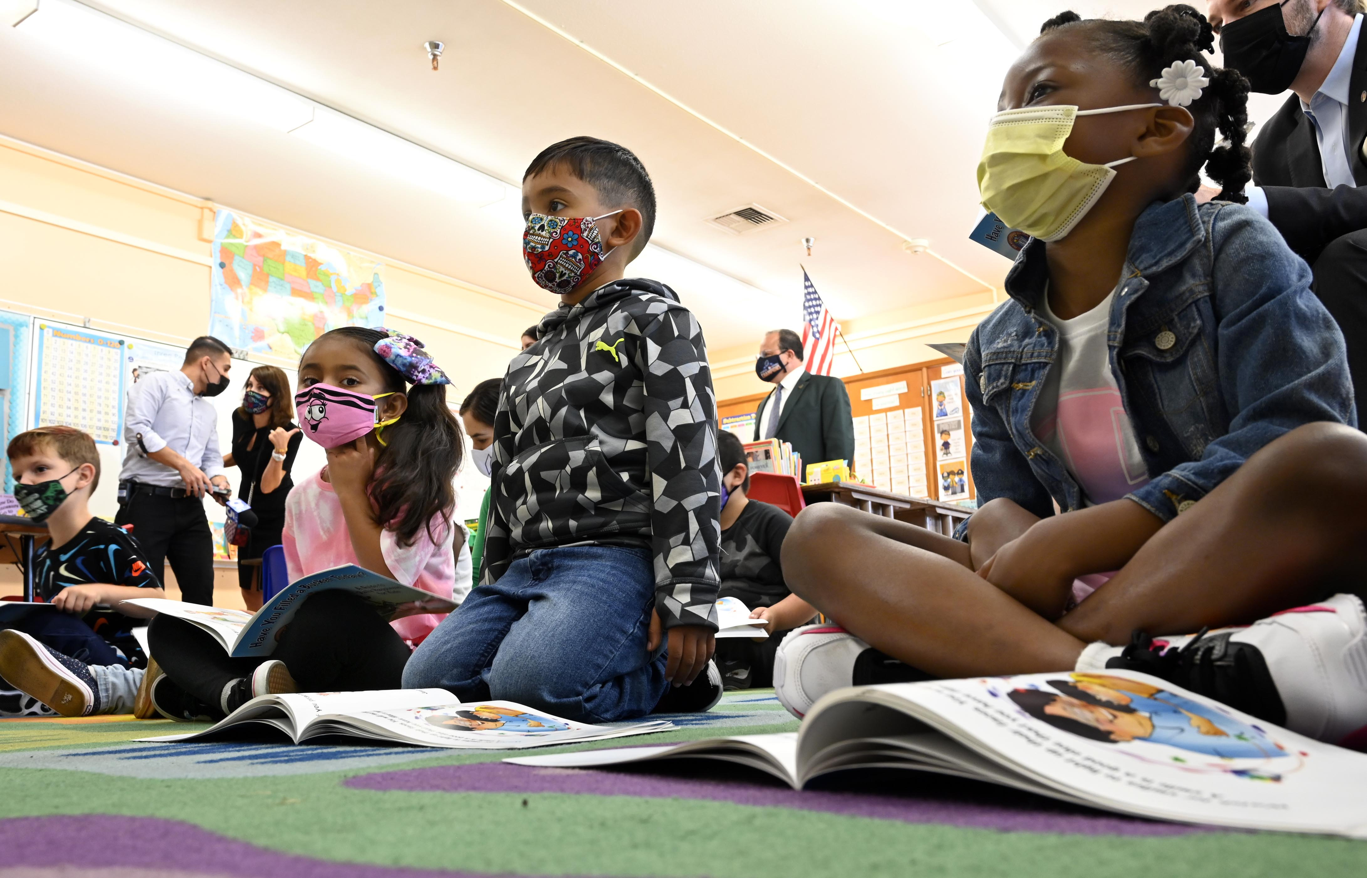 First graders listen as a school official reads a book on the first day of school in Harbor City, Calif., on Monday, Aug. 16, 2021.