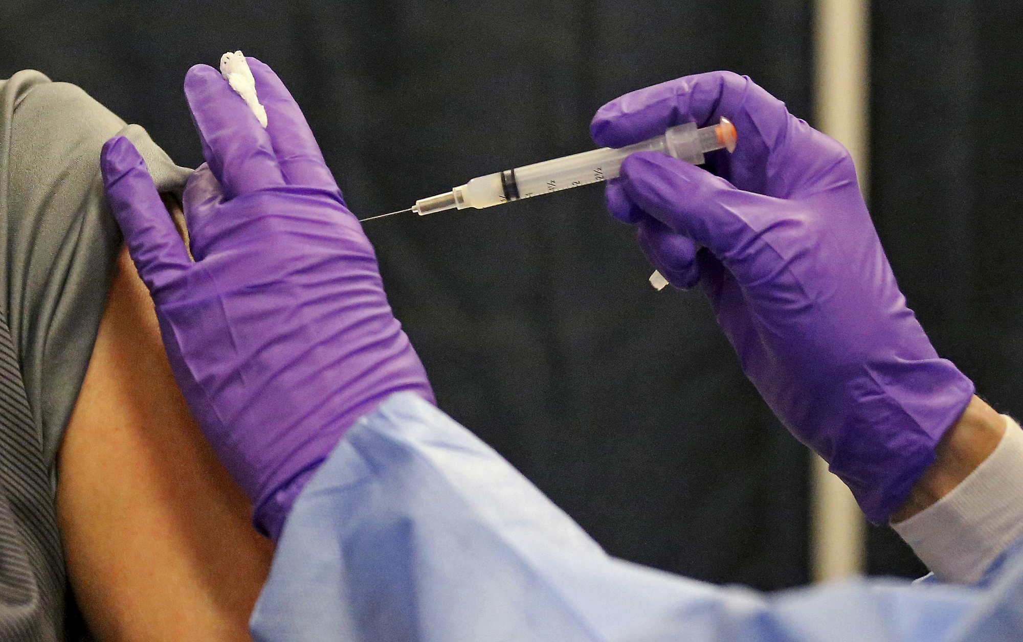 A man gets a COVID-19 vaccine at a mass vaccination site at the Natick Mall on Wednesday, Feb. 24, 2021, in Natick, Mass. U.S. experts are expected to recommend COVID-19 vaccine boosters for all Americans, regardless of age, eight months after they received their second dose of the shot, to ensure lasting protection against the coronavirus as the delta variant spreads across the country.