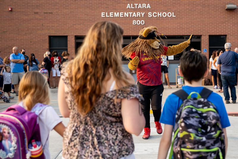 Real Salt Lake mascot Leo the Lion directs traffic as
parents and student arrive for the first day of school at Altara
Elementary in Sandy on Monday.