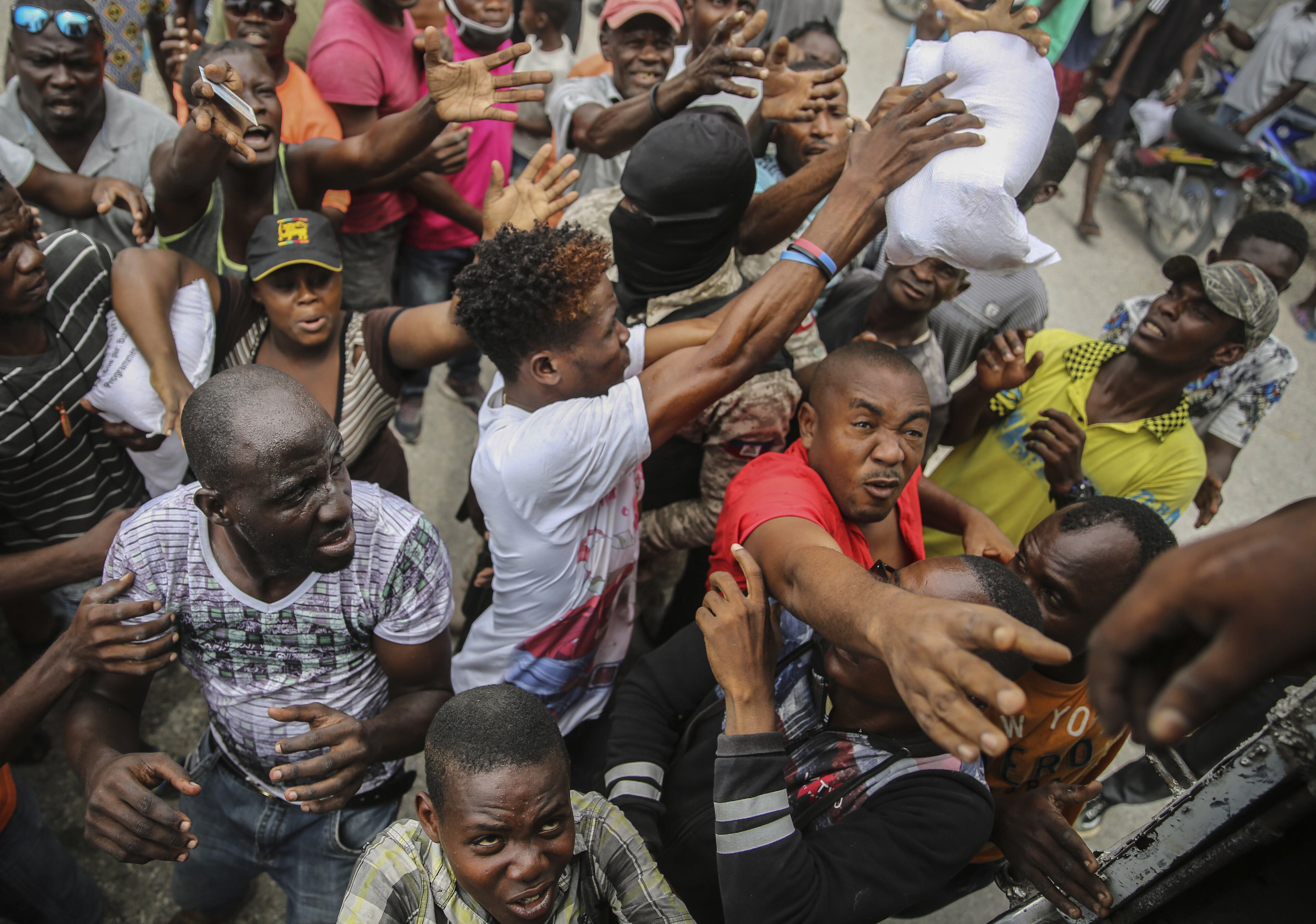 Earthquake victims scramble for a handout of rice at a food distribution place in Les Cayes, Haiti, Monday, Aug. 16, 2021. Haitians are searching for survivors and the dead in collapsed buildings following the powerful earthquake over the weekend as hospitals overflow with patients, as Tropical Depression Grace is predicted to reach Haiti Monday night bringing with it the potential for heavy rain, flooding and landslides.