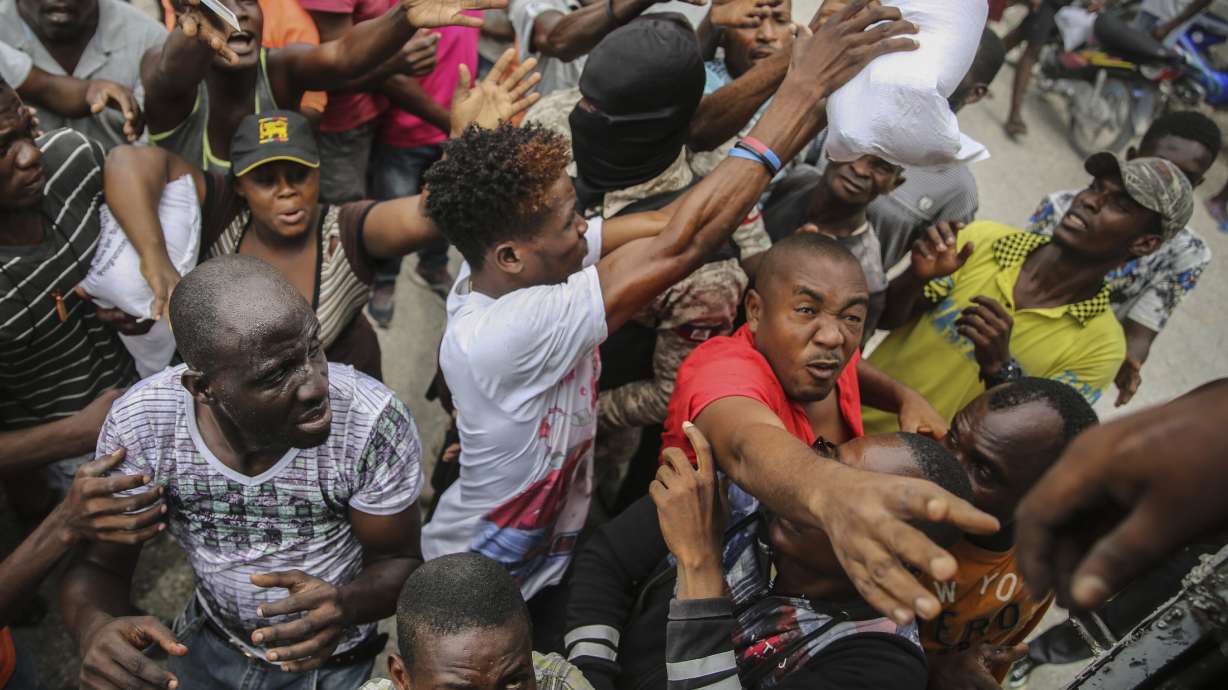Earthquake victims scramble for a handout of rice at a food distribution place in Les Cayes, Haiti, Monday, Aug. 16, 2021. Haitians are searching for survivors and the dead in collapsed buildings following the powerful earthquake over the weekend as hospitals overflow with patients, as Tropical Depression Grace is predicted to reach Haiti Monday night bringing with it the potential for heavy rain, flooding and landslides.