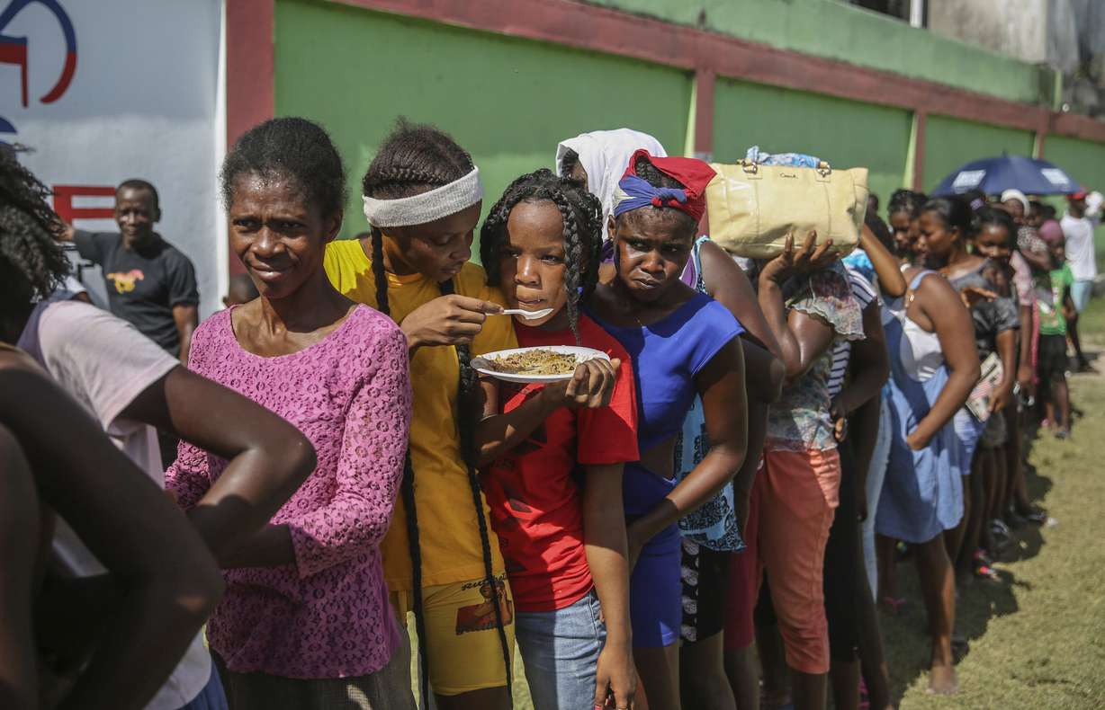 Residents line up during food distribution at a camp for residents displaced by the earthquake in Les Cayes, Haiti, Monday.