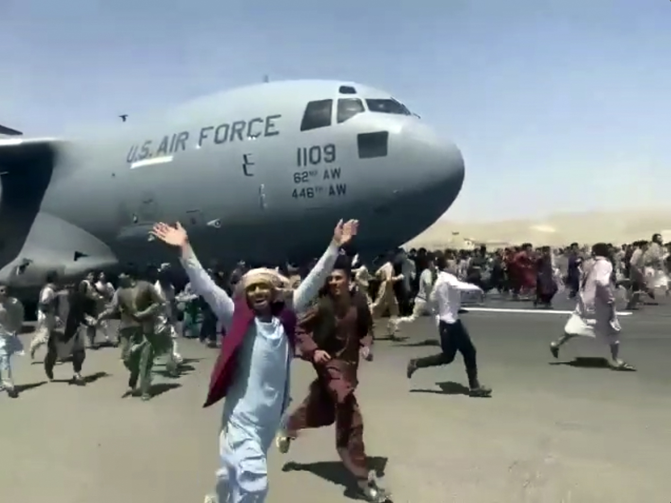 Hundreds of people run alongside a U.S. Air Force C-17 transport plane as it moves down a runway of the international airport, in Kabul, Afghanistan, Monday, Aug.16. 2021. Thousands of Afghans rushed onto the tarmac of Kabul’s international airport.