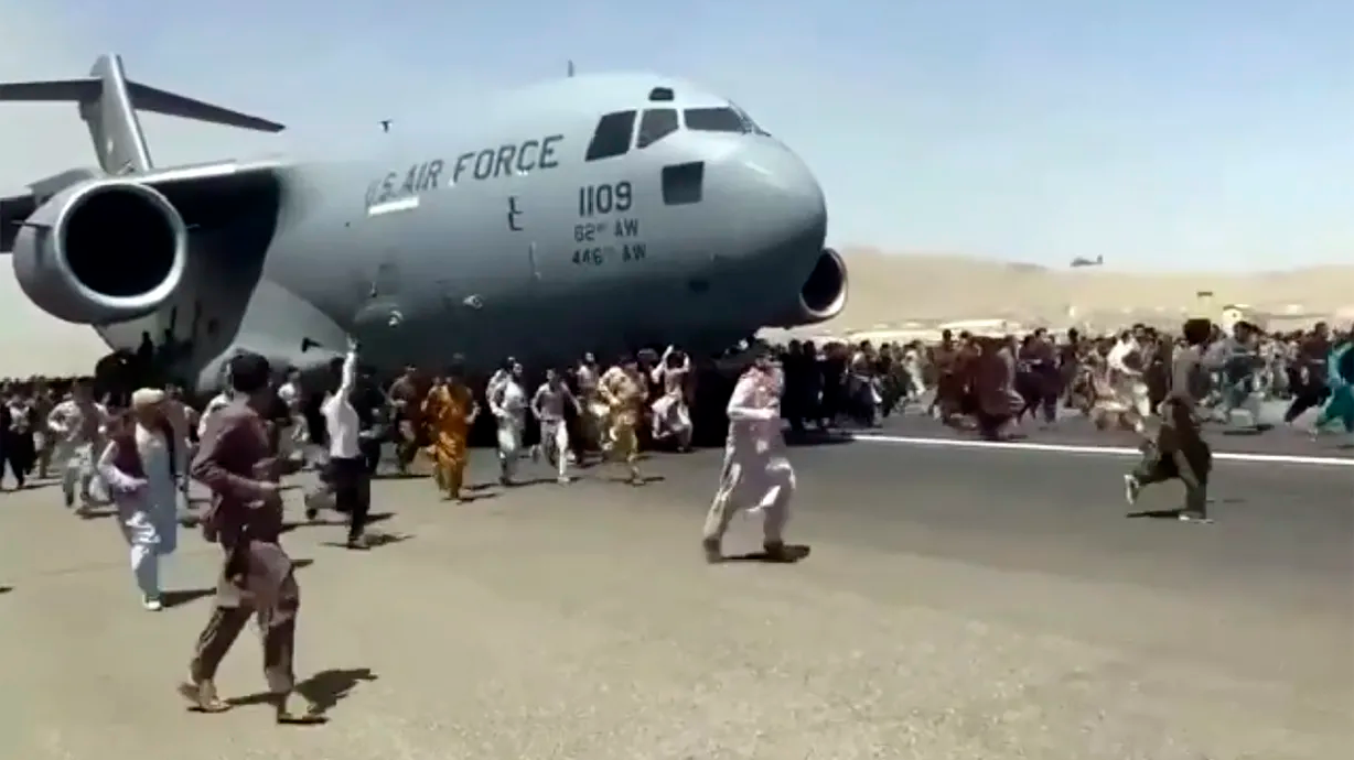 Hundreds of people run alongside a U.S. Air Force C-17 transport plane as it moves down a runway of the international airport, in Kabul, Afghanistan, Monday. Thousands of Afghans rushed onto the tarmac at the airport, some so desperate to escape the Taliban capture of their country that they held onto the American military jet as it took off and plunged to death.